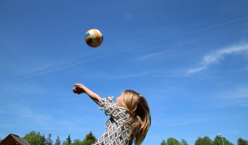 En flicka som kastar upp en boll i luften