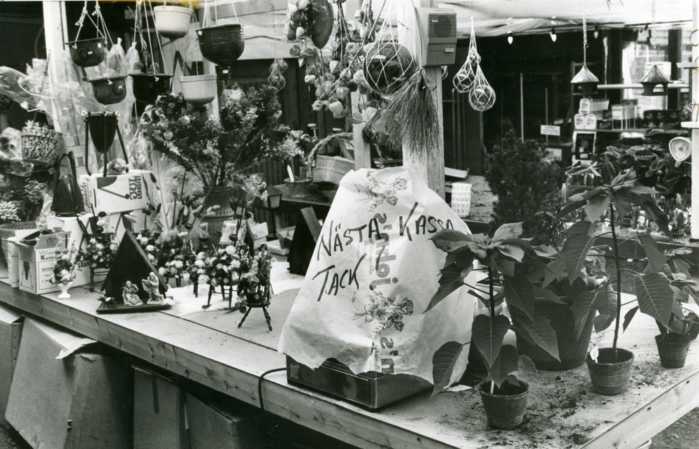 Interiör med försäljningsdisken i John's Plantshop i Brottby. Lokalen togs över av Ingas Bar när verksamheten lades ner 1976.

•Fotografiet ingår i bildserien ”Vardagsliv i Vallentuna kommun” av Rachael Gough-Azmier & Gunilla Blomé, Haga Studios HB.