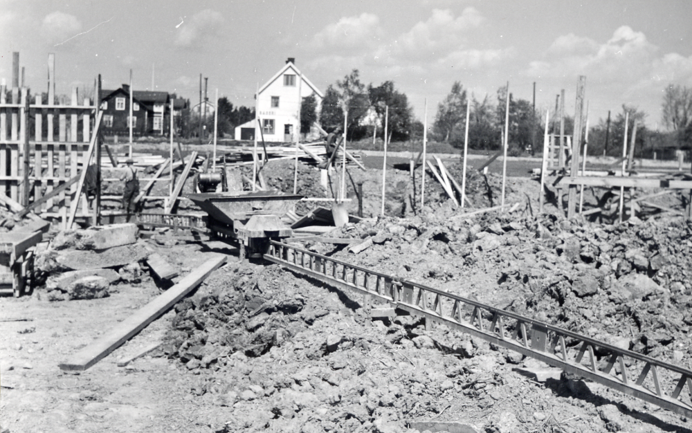 Bild ur tidningsreferat "Vallentuna bygger för 8 miljoner".  Vallentuna kommunalhus  byggs på  Prästgårdsgärdet  invigt 1950.  Rivet 1986 för att lämna plats för ett nytt kommunalhus.  I bakgrunden  bageri  och  tvillingvillorna  eller  syskonvillorna