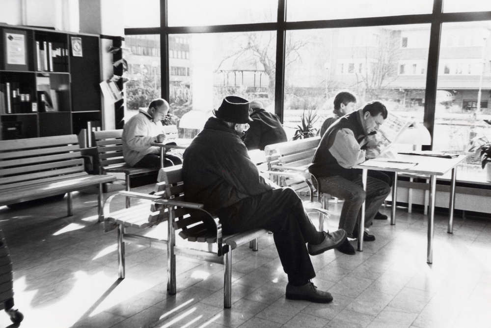 Tidningsläsare i Vallentuna biblioteks foajé en solig marsdag 1995