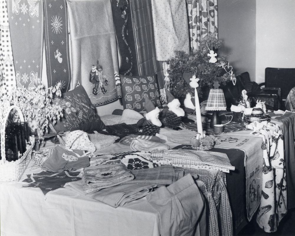Kyrkliga syföreningens auktion eller julmarknad i Klockargården.  På bord och vägg hänger broderade dukar med julmotiv