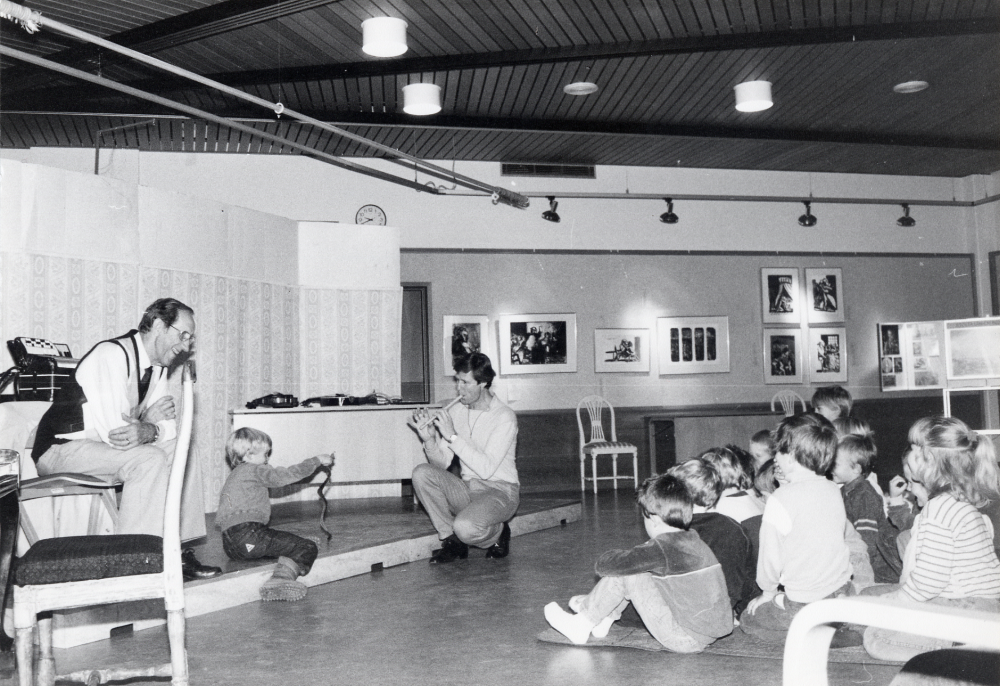 Sven Widén  och hans son  Lars Widén  spelar musik och visar musikintrument för förskolebarn i  Vallentunasalen   Musikprogram för förskolebarn  På bilden spelar  Lasse Widén   flöjt  och en pojke leker ormtjusare