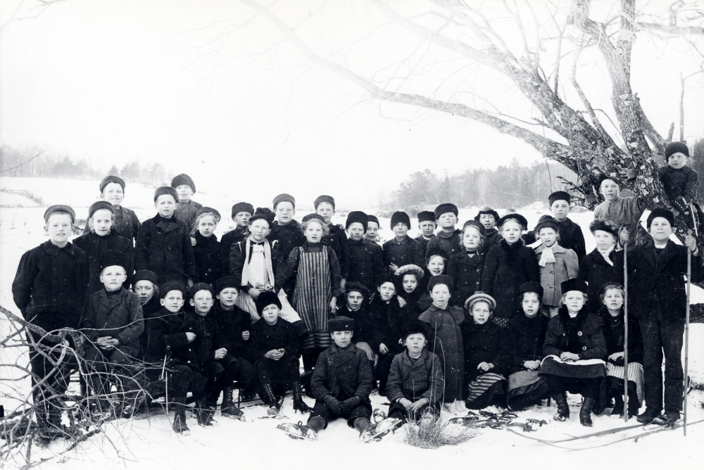 Klasserna 4-6 på utflykt till Stolp-Ekebysjön. Lärare och fotograf Zackeus Carlsson. Sittande fr v Fritz Gustafsson, Signe Gustafsson, Elis Andersson, Martin Lundin, okänd, okänd, okänd, Signe Karlsson, Tyra Jansson, okänd, ,Lilly Johansson, Adele Lundin, Märta Nordström, Greta Örling, Ester Karlsson, Märta Magnusson, och Iris Bergqvist. Stående fr v Allan Céwe, Märta Andersson, Algot Eriksson, okänd, Algot Ekvall, Emmy Andersson, Fredrik Helgöstam, Judith Karlsson, Holger Cewe, Ester Gustavsson, Robert Björklund, Rufus Pettersson, okänd, Hilmer Johansson, Sven Helgöstam, Elis Hedlund, Signe Dahlberg, Erik Rothman, Sally Höglund, Rut Eriksson, Kalle Juhlin, okänd, Ville Fryk, okänd, Albert Pettersson i trädet. Publicerad i Norrtelje tidning 1982 av Sally Andersson i Frösunda