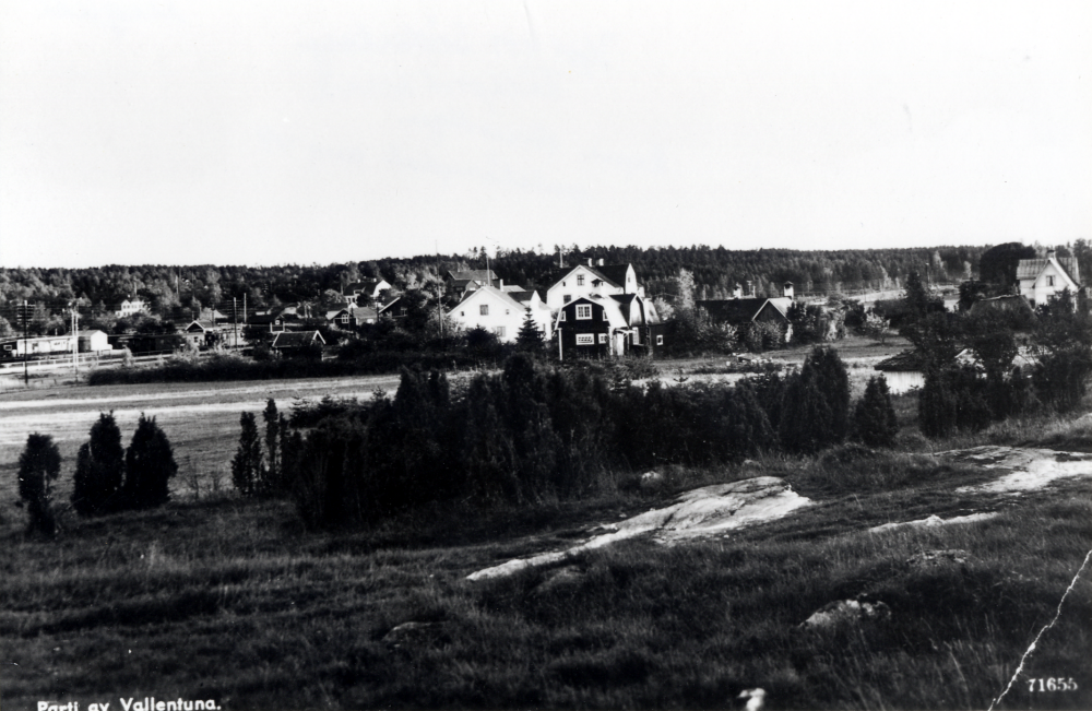 Vy över Vallentuna från Rickebyhöjds enbacke nordväst om järnvägen ner mot stationssamhället.  Det vita huset med brutet tak i bildens mitt är Jonsson affär, t v om det Villa Nysäter, där bl a Sparbanken hade sitt kontor
