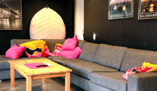Soffa med olika färgglada kuddar. Framför soffan står ett soffbord. 