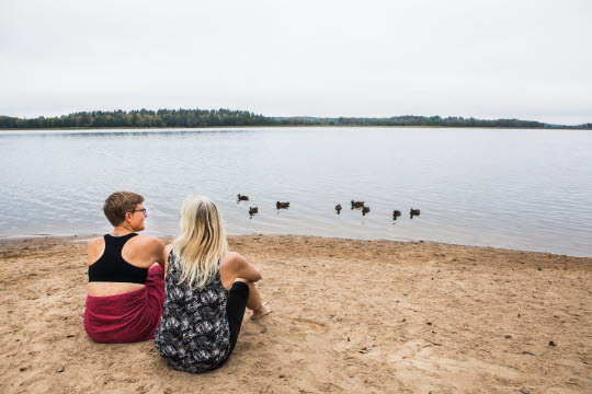 Två kvinnor som sitter på en sandstrand