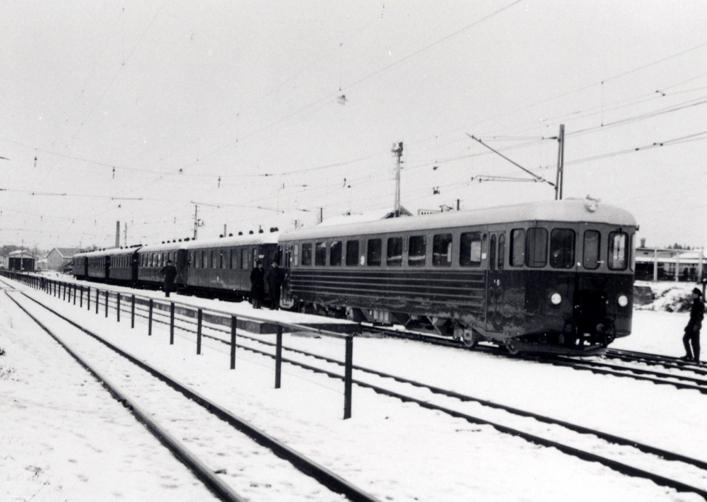 Leveransfotografi av Roslagsbanans nya dieselmotorvagnar från ASJ vid Vallentuna station.  Vagnarna hade nummer 3110-3112 och kallades "Rydbergarna" efter  SRJ:s VD Åke Rydbergh.  Tyvärr var vagntypen i drift endast ett tiotal år, bl a p g a otillräcklig luftkylning, luftintagen satt så lågt att snö och löv sögs in och hindrade kylningen av motorerna med överhettning och driftstopp som följd.  I bakgrunden syns motorvagnstallarna norr om stationsområdet och gaveln på Vallentuna tegelbruk.  T h byggs Maskin Tellus nya lokaler