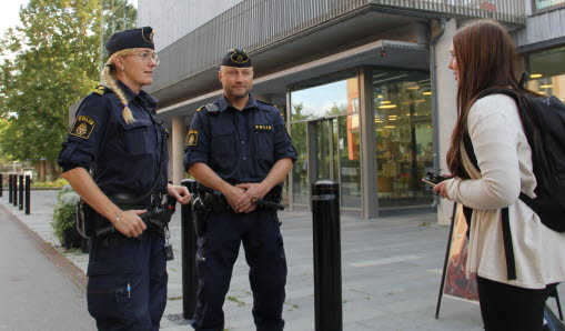Två poliser samtalar med en ungdom framför kulturhuset