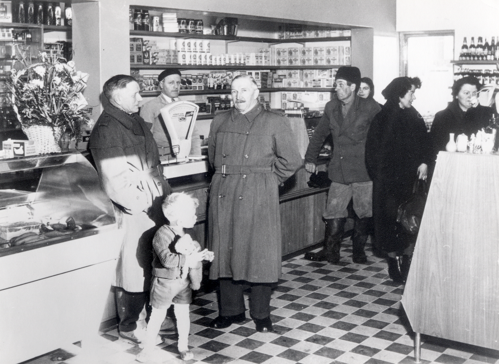 Hulda Maria Eriksson och Gösta Eriksson övertog Sursta handel 1944. Nytt affärshus bygdes 1955 och var i drift till 1963. I affären fanns 1955-1975 en biblioteksfilial, vilken också sköttes av makarna Eriksson. Bilden är från invigningen 1956. Fr v Oskar Rickberg pojken är Erikssons son Christer Eriksson Gösta Eriksson bakom disken, Oskar Söderlund Gustavsberg, Ernst Nyberg Grana fotografens fru, Gullan Mellbom Norrbacka och Signe Gustafson Sursta. Se Lanthandlare i vallentunasocknarna vid Roslagsbanan