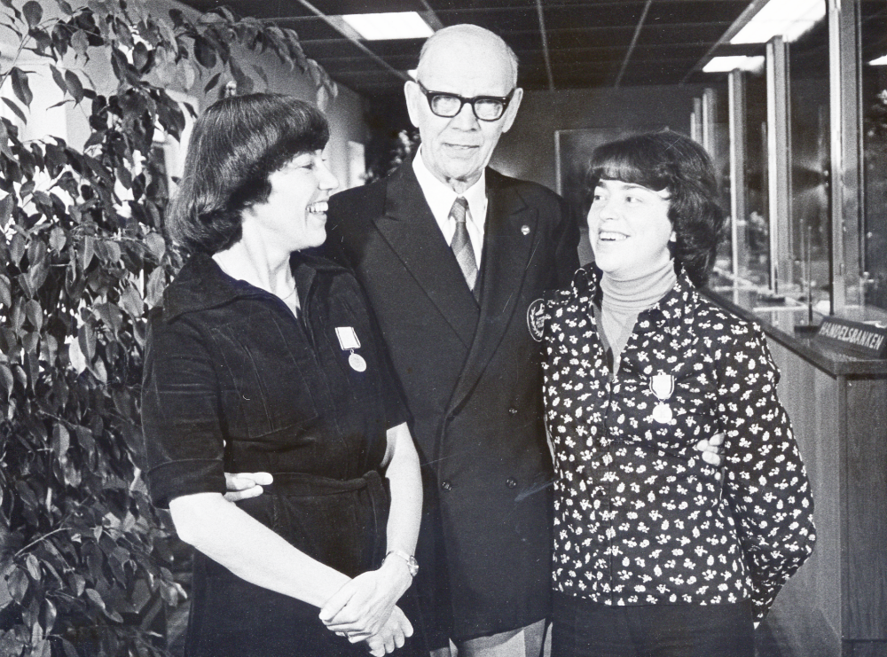 Simmaren och flerfaldige medaljören Arne Borg tillsammans med Ingrid Klint och Maine Gräns på Handlsbanken i Vallentuna. Damerna har fått varsin medalj från 1920-talet av Arne Borg för 'vänligt bemötande'