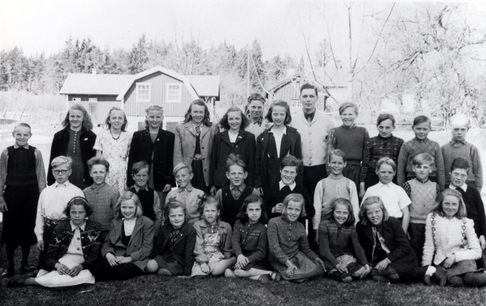 Läraren Gösta Abrahamsson med skolbarnen i Vada skola. Stående i bakre raden fr v Gunnar Söderström, Britt Karlsson, Ulla Jonsson, Kerstin Törnblom, Kerstin Gustavsson, Gunvor Ericsson (Lundberg), Svea Jansson, Ingegärd Sjögren, Karl-Gustav Adegren, Olle Andersson, Ingvar Gustavsson och Göte Sjögren. Mellanraden fr v Barbro Pettersson, Kerstin Alstermark, Gun-Britt Frölin, Solweig Johansson, Kerstin Wallerts, Elsy Sjögren, Anna-Greta Jansson, Sonja Sjögren och Edit Jansson. Nedersta raden fr v Lennart Gustavsson, Kjell Johansson, Lennart Törnblom, Dick Gustavsson, Sten Sjögren, Ernst Petterson, Sven-Erik Ericsson, Lasse Mokvist, Roland Söderström och Sven-Erik Pettersson