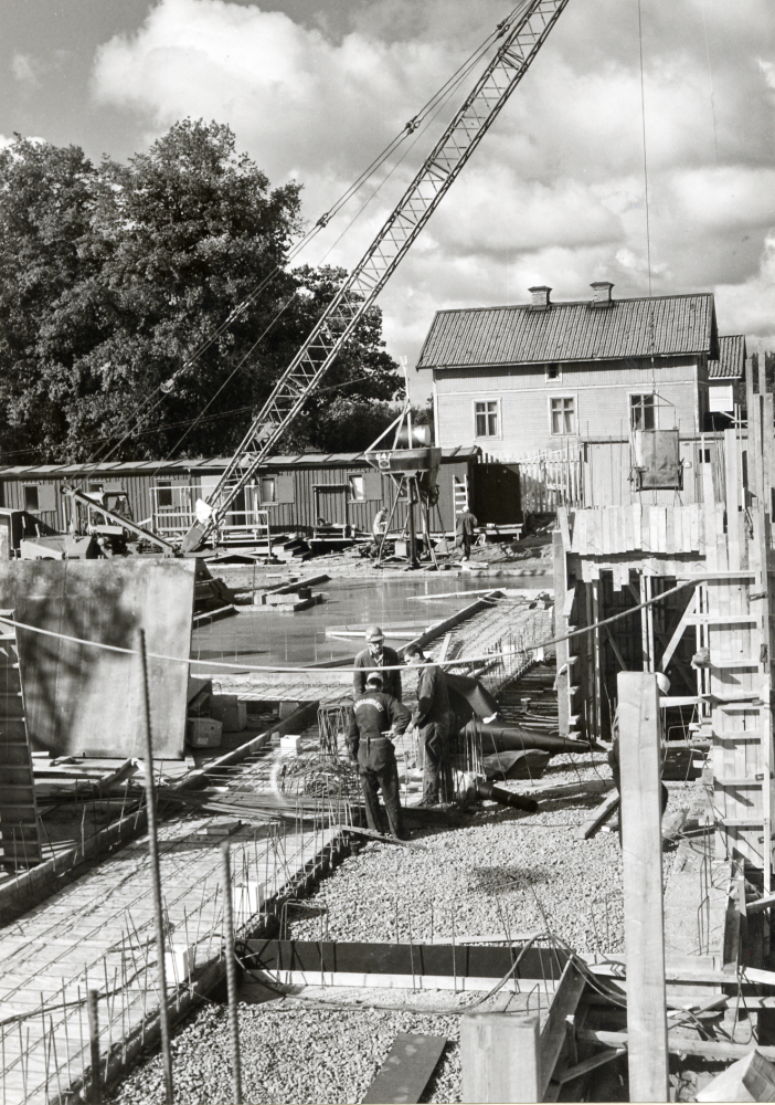 Nytt och gammalt. Grunden läggs för Vallentuna nya pensionärshem Väsbygården. I bakgrunden en flygelbyggnad till Väsby gård som revs 1971