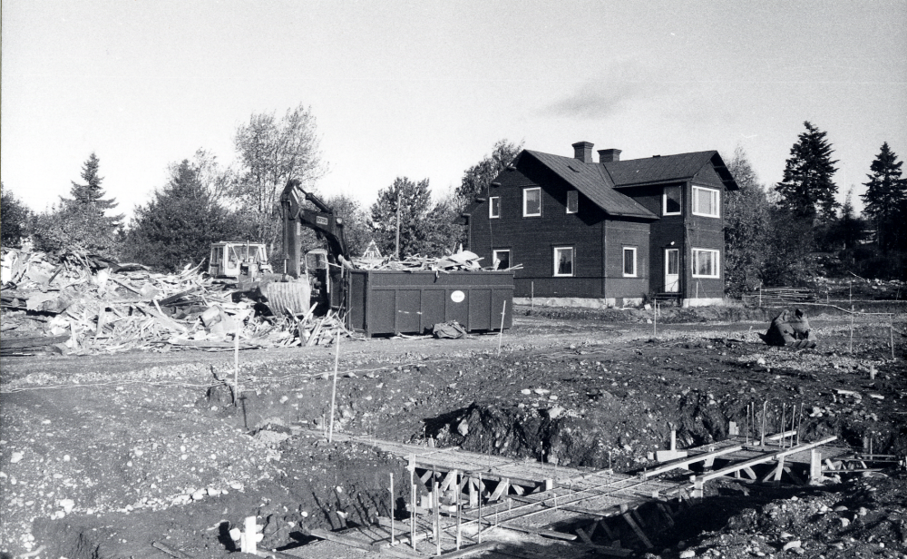 Syskonvillorna eller Tvillingvillorna med adress MÖrbyvägen. Den södra villan rivs för att lämna plats för det nya förvaltningshuset Tärningen, vars grundarbeten syns i förgrunden. En grävskopa lastar i en container