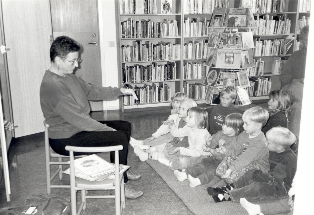 Brita Hampling leder sedan många år sagostunderna i Vallentuna bibliotek.  Här sitter hon tillsammans med några barn i Internationella rummet.  Dokumenterat i samband med "Den stora dokumentations- dagen" i alla bibliotek - 14 oktober 1996