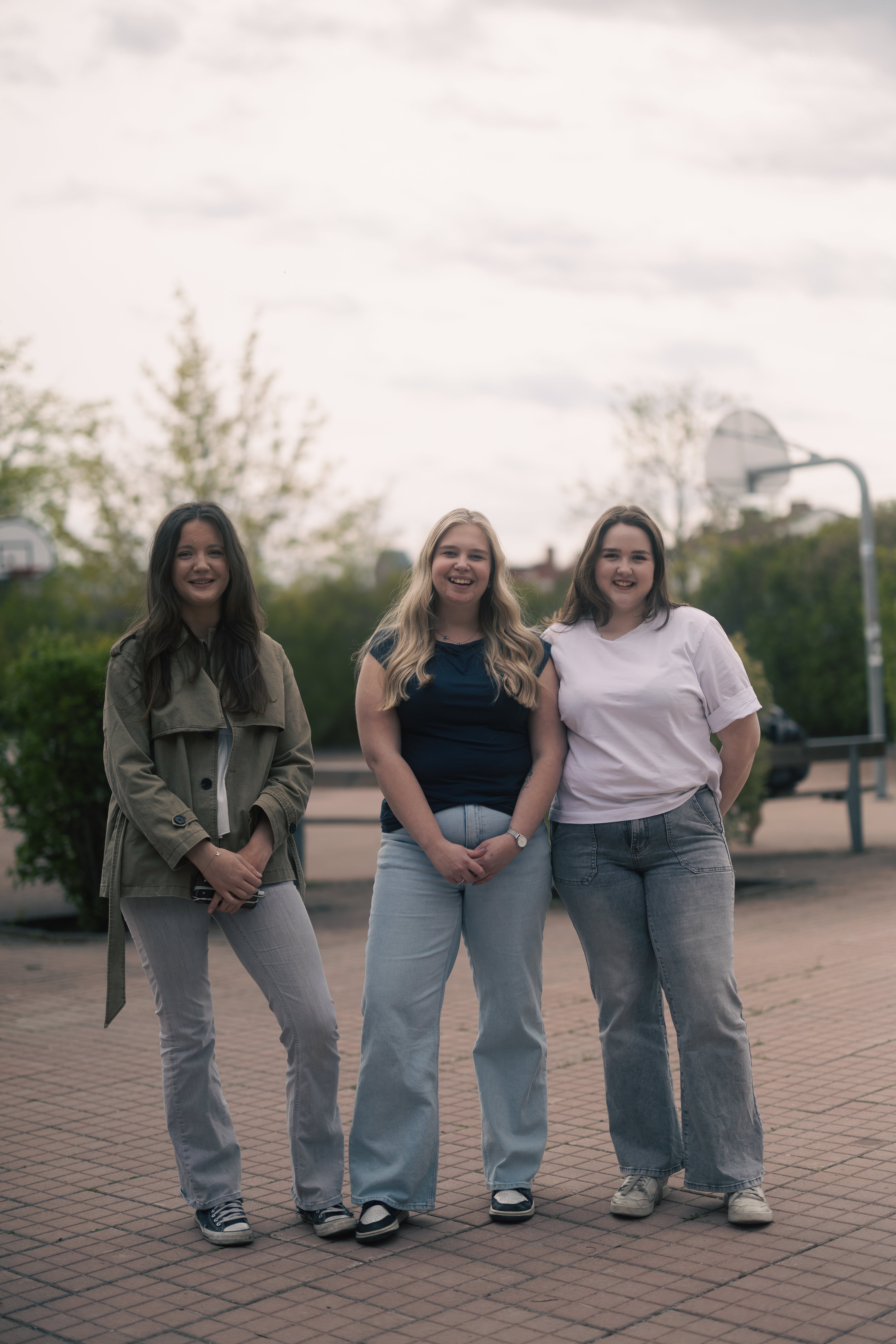 Tre tjejer som är gymnasieelever och umgås tillsammans på framsidan av Vallentuna gymnasium.