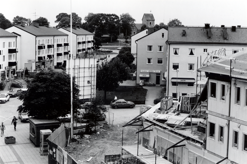 Tuna torg med kommunalhusbygget t h.  I bakgrunden i bildens mitt bostadshusen längs Centralvägen.  Längst bort syns Vallentuna kyrka