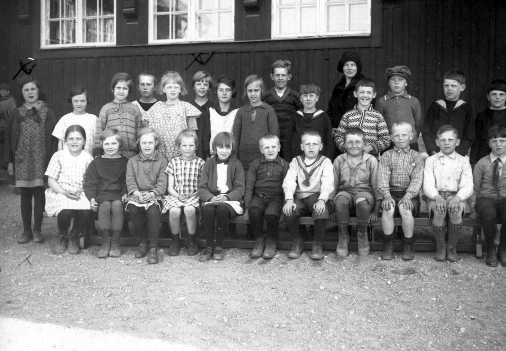 Utanför Röda skolan i Hjälmsta står lärarinnan Edit Lindström med skalbarnen i klass 5. I bakre raden tv markerat med ett kryss, står Maj Linder, senare gift med Ragnar Pettersson.