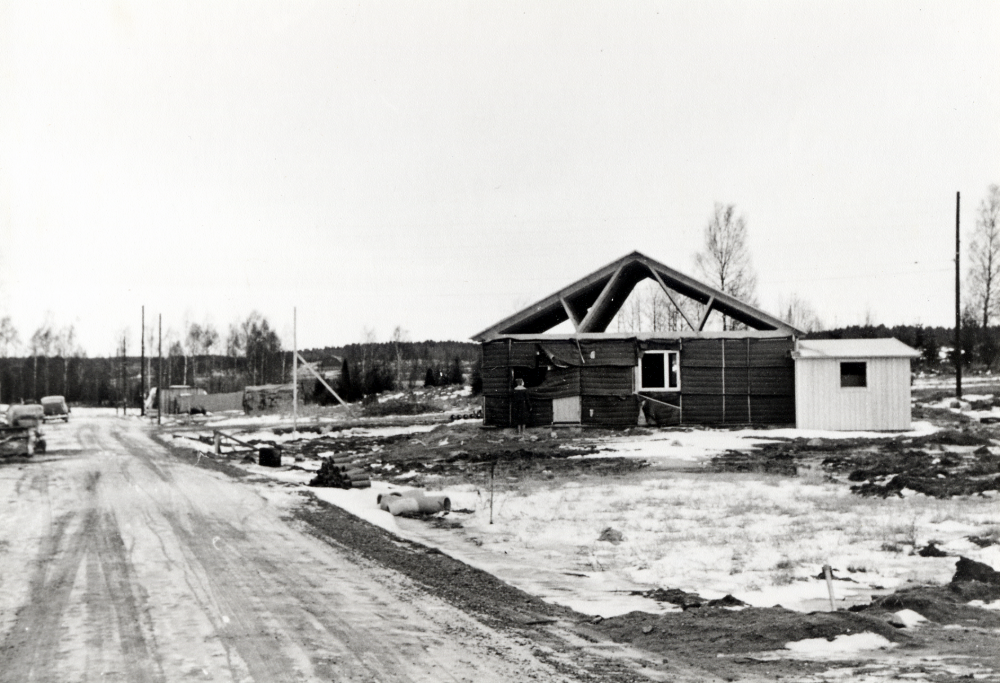 Ny villabebyggelse på Aspvägen i Karby, Brottby våren 1964.  Huset som byggs av Gunnel och Jonas Carlstedt, får adress Aspvägen 2.  Kvinnan utanför huset är Gunnel Carlstedt