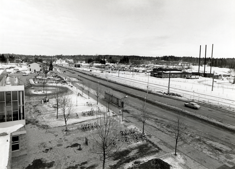 Vy från Tunahuset åt nordost. Tv syns gaveln av Torghuset, i bildens mitt Banvägen och Roslagsbanans spårområde med motorvagnsstallet. På andra sidan järnvägen pågår bygget av Vallentuna nya sjukhem med distriktsläkarmottagning. Skorstenarna t h tillhör Vallentuna värmeverk. Det ljusa huset t v om Banvägen är Centrum-Bio