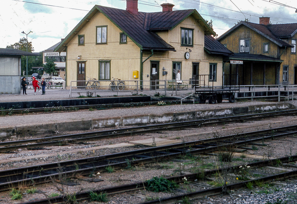 Vid Vallentuna station. Det lite mörkare huset till höger är det gamla järnvägshotellet med restaurang som kallades Flugan. Byggnaden brann ner 1970. Huset till höger är Vallentuna järnvägsstation som revs 1972. 
Bildserie: Vallentuna på 1960-talet.