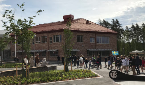 Hagaskolans huvudbyggnad med folksamling utanför som firar.