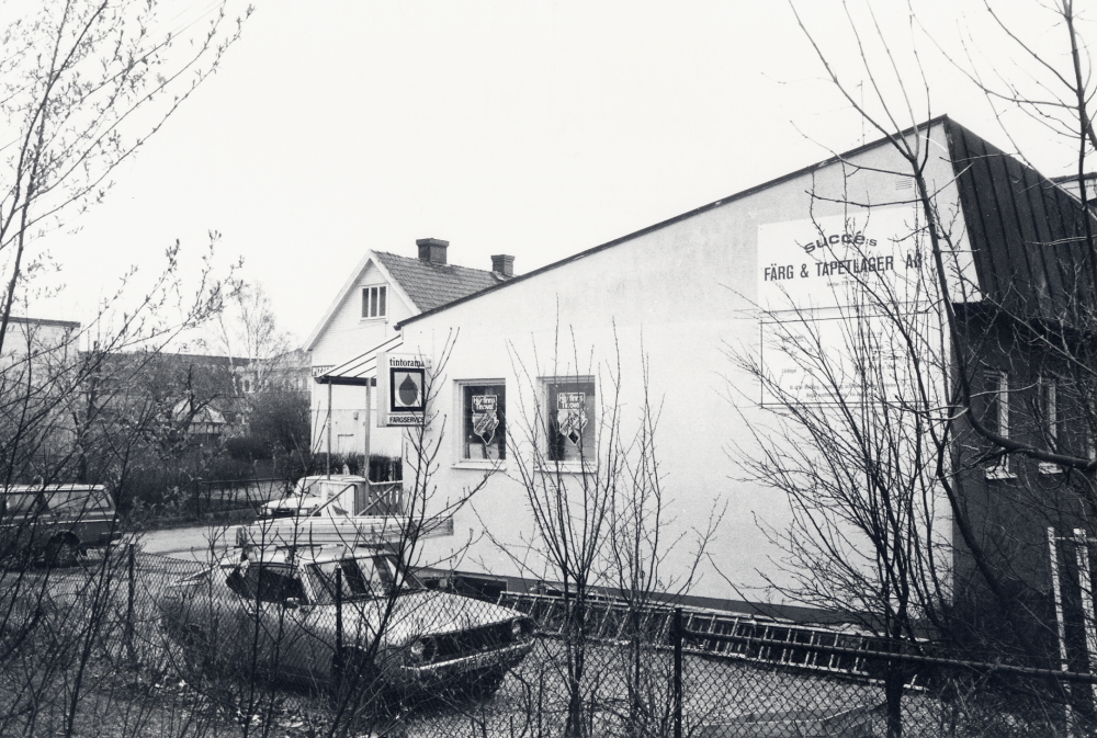 Succé färg och tapetlager AB i Vallentuna centrum med adress Allévägen 4.  Hösten 1990 rivs alla hus i kvarteret och ett nytt bostads-, affärs-, och företagshus byggs i dess ställe.  Succé flyttar till Okvista industriområde