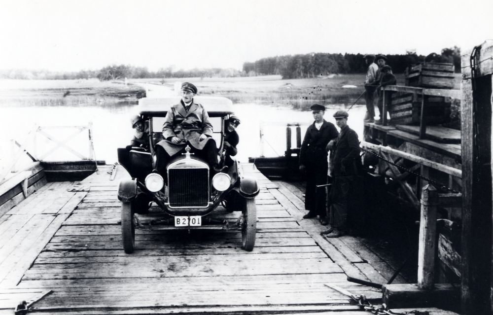 Utflykt med personbil på obekant färja. På bilen sitter Knut Eriksson, t v Signe Johansson från Karlsborg i Angarn och t h Knuts fru Aina Eriksson.
----------
2021-02-19 kompletterande uppgifter: Knut Erik Eriksson, född 1893-09-15 i Stockholm (Adolf Fredrik Pro Patria), men bott i Östra Ryd (Eriksö och Norrkulla) till 11 maj 1918. Död 1976.
Aina Maria Adelina Olsson, född 1888-09-16 i Vaxholm. Bott på Skarpö i Vaxholm, men flyttat till Engarn, Österåker 1903. Död 1971.
Knut och Aina gifte sig 1916. 1918 flyttade paret från Östra Ryd till en bondgård i Angarn (Örsta, Norrgården). 1918 föddes dottern Inga Lisa. Sedan föddes ytterligare tre barn, Henry, Gelly och Margit. Yngsta dottern Margit dog i 25-årsåldern efter lång tids sjukdom. De övriga tre blev samtliga över 90 år.
Förutom att vara lantbrukare, så var Knut även nämndeman i ett flertal år.
Med på bilden är även Signe Johansson, hennes make är fotografen. Paret var nära vänner med Knut och Aina och de hade handelsboden Karlsborg i Angarn.