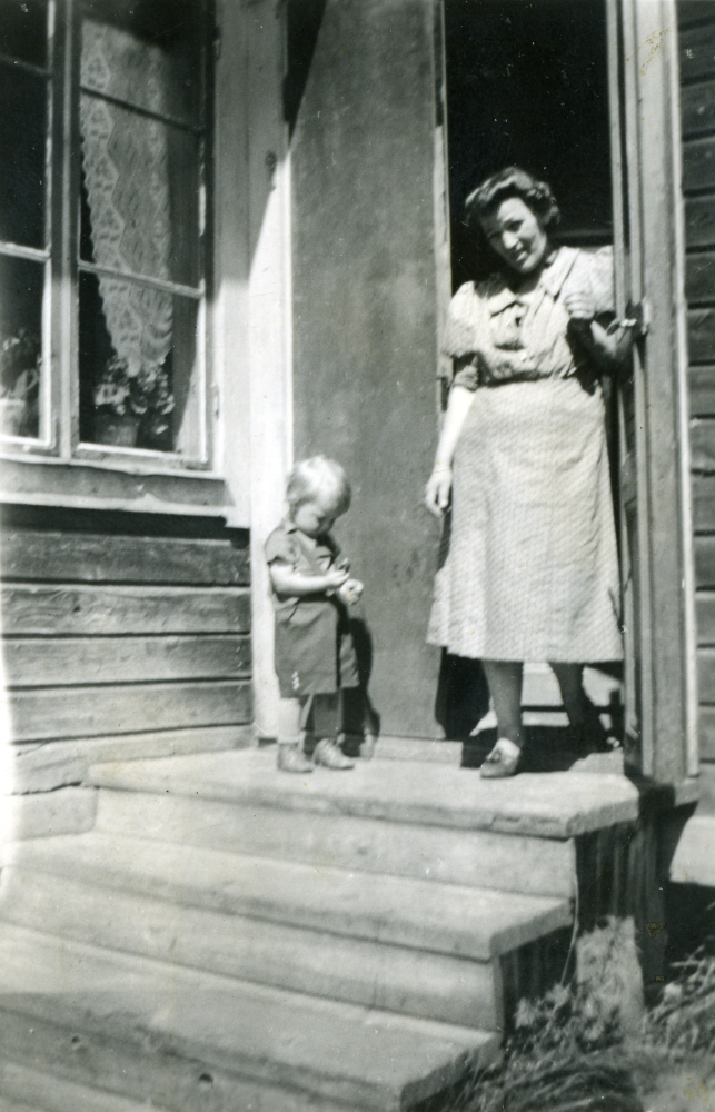 Sven Karlsson 1,5 år och mjölkerskan Elsa Karlsson står en söndag på trappan till en av bostäderna för de anställda vid Husa gård.