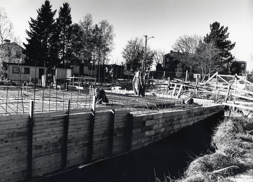 Pingstkyrkan i Vallentuna under byggnad hösten 1978. I bakgrunden flerfamiljshus på Mörbyvägen. På bilden arbetar man med gjutning av grunden