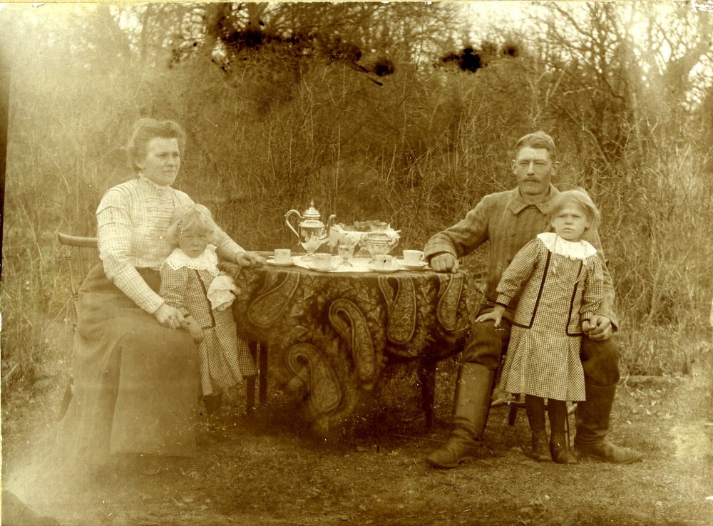 Kaffestund vid Gällsta gård i västra Vallentuna omkring 1912. Vid bordet sitter fr v Helga Ek, född Kahlson 1886 på Grana gård V-a, med dottern Ester, född 1908, och Isidor Ek född 1884, med dottern Irma född 1906. Helgas far var August Theodor Kahlson. Han var fjärdingsman och för att undvika förväxling med syskonen bytte han stavning på efternamnet från Karlsson eftersom det kom så mycket post till alla Karlsson, bodde på Åsta i Angarn