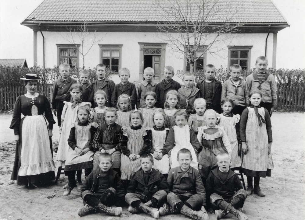 Lärarinnan Hanna Krantz tillsammans med skolbarnen utanför Klockargården. I tredje raden nedifrån nr 3 fr v är Hildegard Olsson, Åby gård