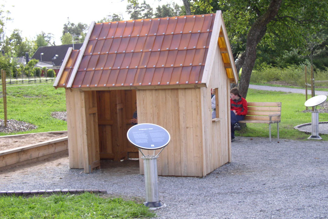 en trästuga i temaparken vid täby kyrka