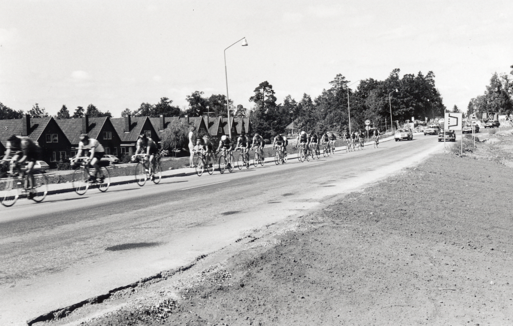 Deltagare i cykelloppet Postgirot passerar Bällsta på Stockholmsvägen i augusti 1973.  T v syns de s.k. engelska villorna på Lagerfelts väg