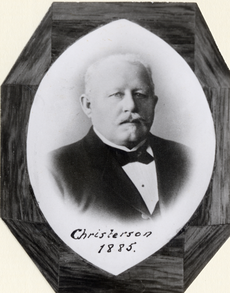 Del av tavla med stationsföreståndare vid Vallentuna järnvägsstation Christersson 1885. Foto monterat i trä. Tavlan hängde i expeditionen i stationshuset som revs 1971. Tavlan hänger nu i Åbybergskyrkans cafeteria Nyponstigen - Nypåstigen, Uppgift om fotoår saknas.
