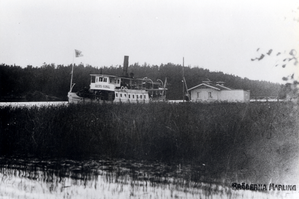S/S Åkers Kanal i Garnsviken vid Hakunge brygga, Össeby-Garn.  Vid denna tid ägdes båten av Waxholmsbolaget enligt flaggan i fören. 

Uppgift om fotoår saknas.