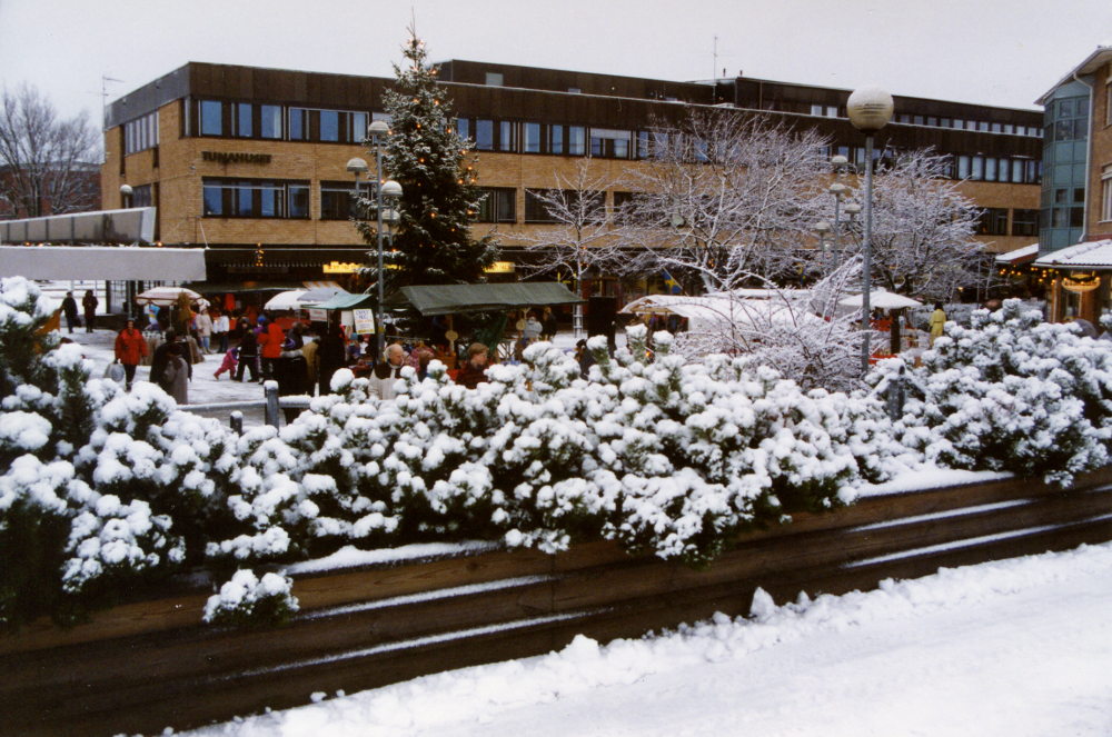 Vallentuna julmarknad på Tuna torg. Julgran och julstjärnor smyckar torget. Vinter. Snö.