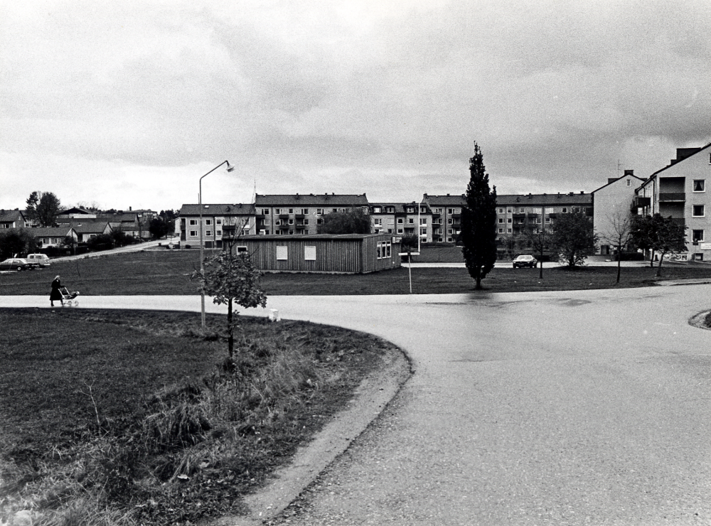 Utsikt från infarten mot Vallentuna kyrka ut mot Prästgårdsgärdet Fr v enfamiljshus med adress Gärdevägen i bildens mitt i förgrunden Leksakshuset tidigare Apoteket Runan med flerfamiljshusen bakom med adress Skördevägen T h syns gaveln på husen vid Centralvägen