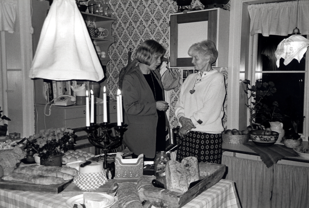 Vallentuna staffanssångare firar 10-årsjubileum och avslutningsfest på Stora Benhamra i Vada.  I köket är knytkalaset uppdukat och där samtalar Ingrid Ullman och t h Barbro Eketorp, som tidigare restaurerat och bott i gårdens huvudbyggnad