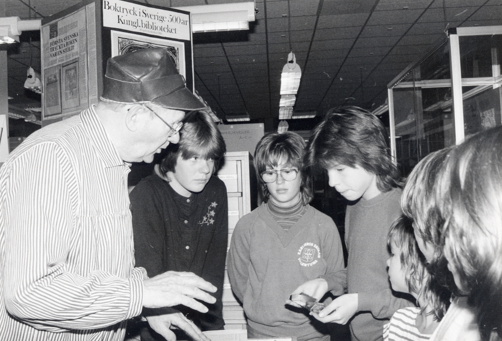 Svenska boktryckerikonstens 500-årsjubileum 1983 Boken fyller år uppmärksammades i Vallentuna bibliotek med utställningar och program. Här besöker sättare Gustav Sandberg biblioteket och visar hur en boktryckare arbetar under tema Bland stilar och kaster när biblioteket har söndagsöppet den 9 oktober