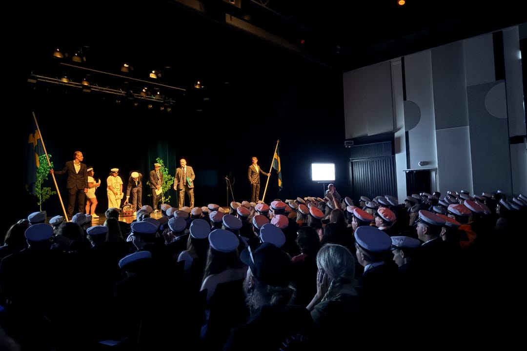 studentavslutning i teatern med alla elever sittandes i bänkarna med vita studentmössor