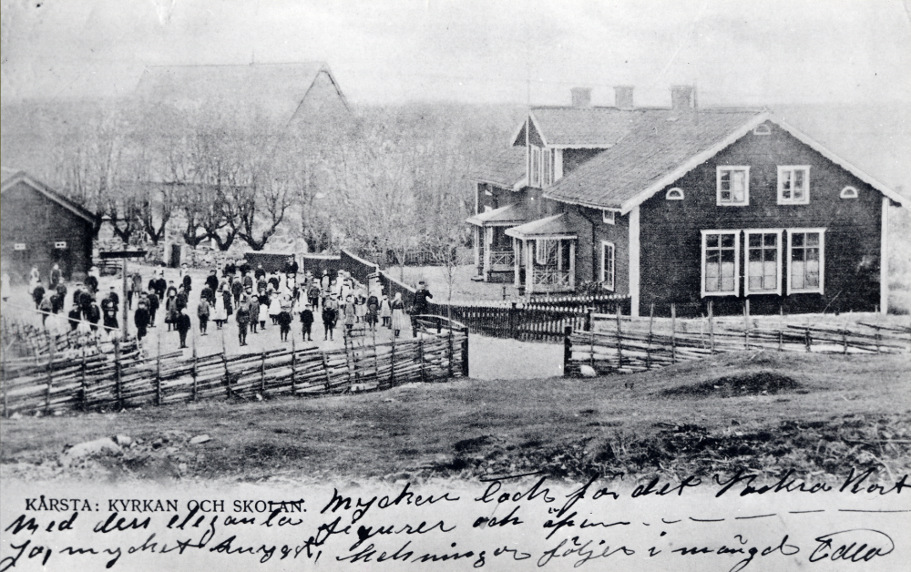 Kårsta skola  med  Kårsta kyrka  i bakgrunden sett från klockstapelshöjden. Skolbarnen står t v om vägen ner genom Kårstaby