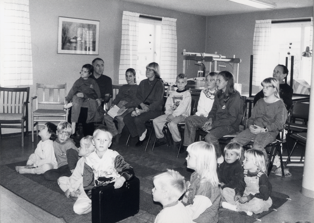 Bibliotekssöndag i Karby bibliotek med bokhjul, bokförsäljning och barnteater och smakprov från Össebyamatörerna.  Medarrangör är Vallentuna biblioteks vänner som också deltar med funktionärer.  I PRO-lokalen kan barnen med föräldrar titta på barnteatern Kofferten av och med Thomas Lundkvist.  Barnen på golvet längst t v är Sam Heiligers och Joel Meier.  På stolarna  sitter från vänster Jacques Heiligers med Nadja i knäet, Anna Meier, Ulla Meier och Martin Meier.  Övriga är okända