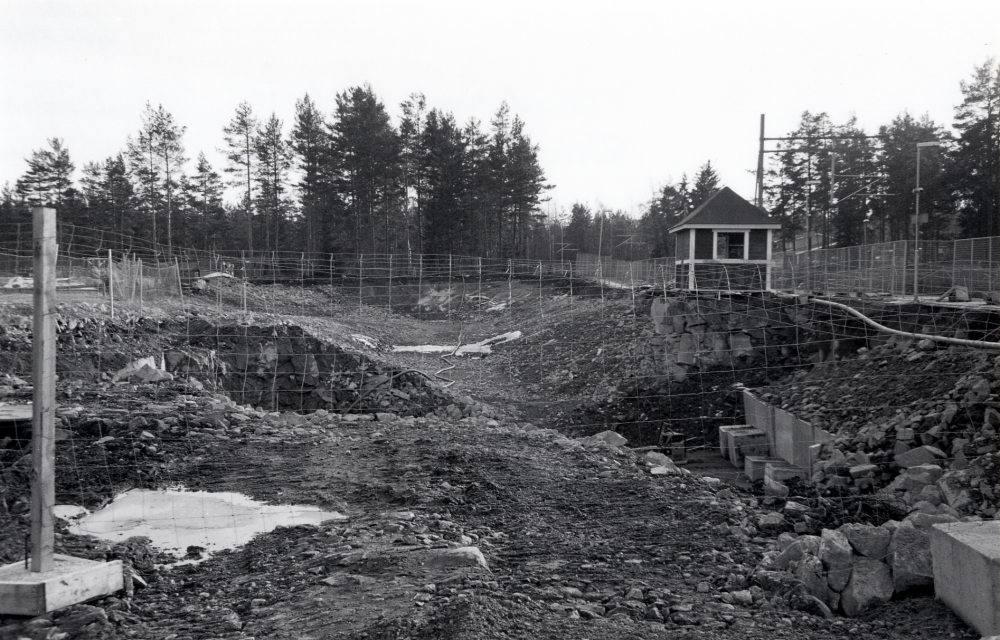 Det pågår stora markarbeten  när gångtunneln byggs under Roslagsbanan vid Kragstalund våren 2002.  Den nybyggda väntkuren, vars original tidigare stod vd Byle hållplats, ser ut att stå på ravinens kant.  Undergången byggs samtidigt som den nya Bällstabersskolan