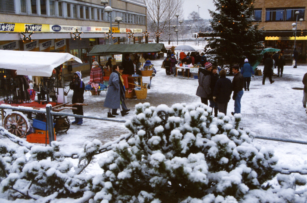 Vallentuna julmarknad på Tuna torg. Julgran och julstjärnor smyckar torget. Vinter. Snö.
