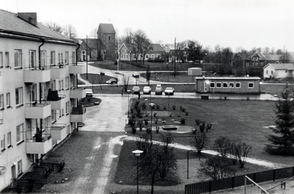 Utsikt mot söder från en lägenhet med adress Skördevägen. T v syns baksidan av husen med adress Centralvägen, parken samt baracken med apoteket Runan. I bakgrunden syns Vallentuna kyrka och Klockargård samt längst t h den första villan på Prästgårdsgärdet