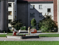 Centralvägen. En förälder med barnvagn går förbi. Ett litet barn leker i sandlådan. Centralvägen bebyggdes med bostäder och affärslokaler i början av 1950-talet och brukar kallas Vallentunas första affärsgata.
Bildserie: Vallentuna på 1960-talet.