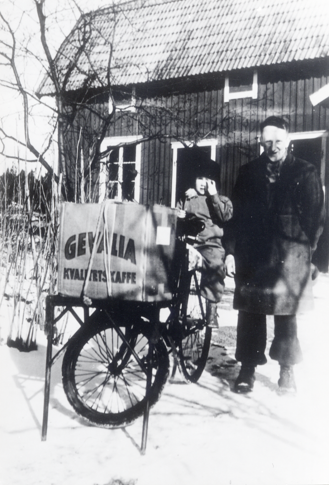 Sven Widegren, son till affärsinnehavaren Elin Widegren-Andersson har lämnat varor lastade på en  cykel  till prästgårdarrendatorfamiljen Carlsson. På pakethållaren sitter systersonen  Jan Ekstedt.  Affärens rätta namn är A Widegrens eft E Andersson. Läs mer i Lanthandlare i vallentunasocknarna vid Roslagsbanan.