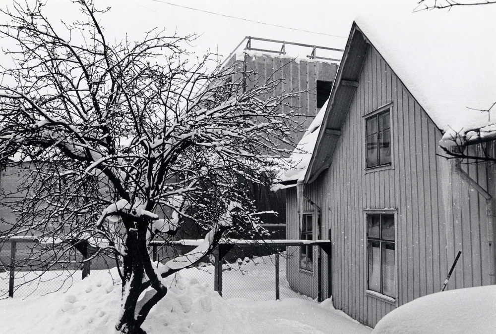 Utsikt mot förvaltningshuset Tärningen mot norr med baksidan av affären Kära Barn i förgrunden t h. Tärningen har ännu inget tak men byggt två våningar högt