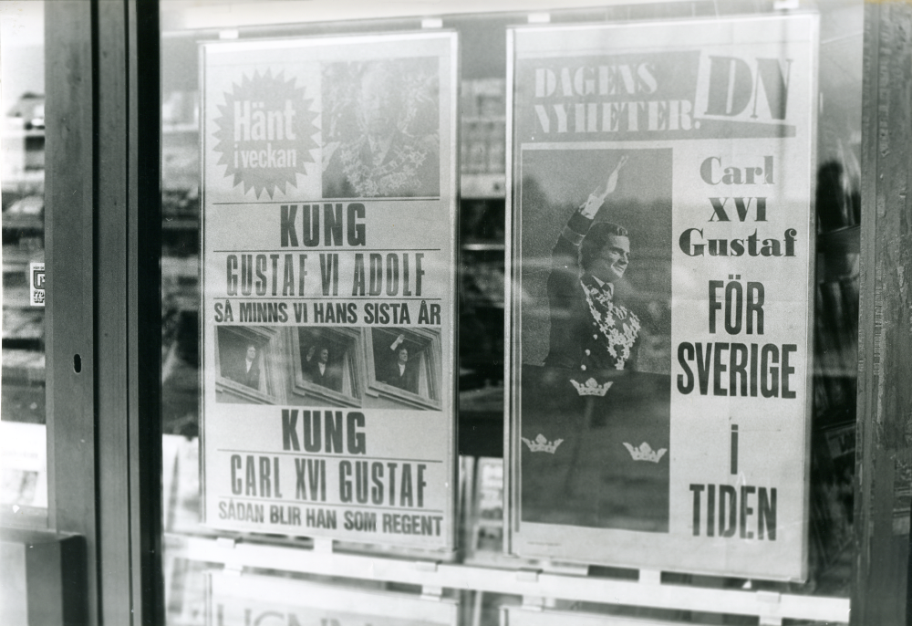 I fönstret på Pressbyråns nya lokal i Tunahuset sitter två löpsedlar om kung Gustaf VI Adolf (död den 15 september 1973) och Sveriges nye kung Carl XVI Gustaf.
•Fotografiet ingår i bildserien ”Vardagsliv i Vallentuna kommun” av Rachael Gough-Azmier & Gunilla Blomé, Haga Studios HB.
