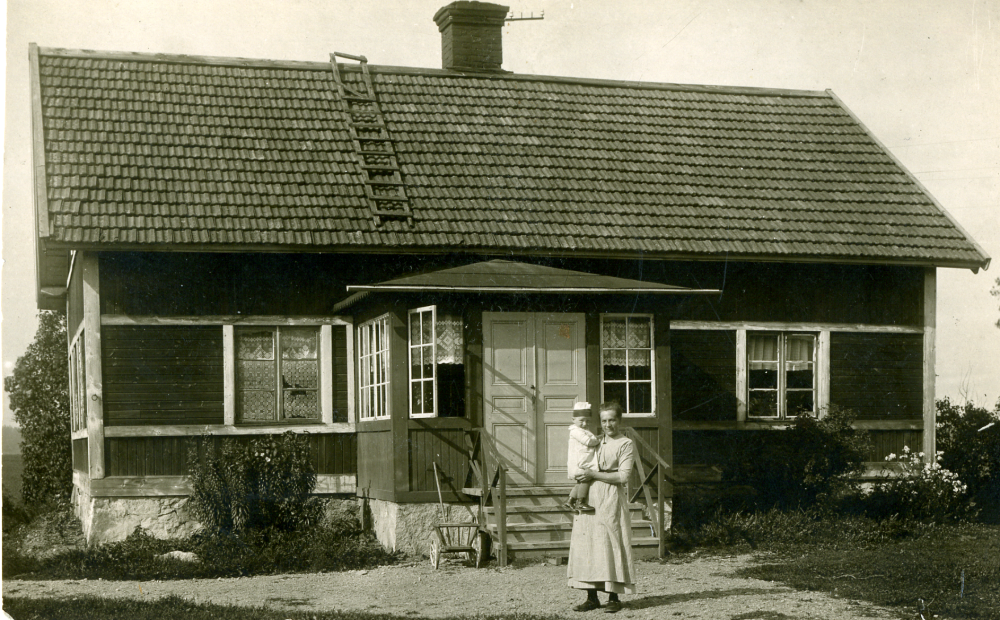 Åsta gård i Angarn.  "Tant Olsson" står utanför huset med en av flickorna i famnen